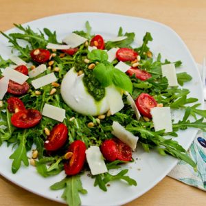 Bild zeigt einen Teller mit Burrata, Rucola, Tomate und Pesto alla Genovese.