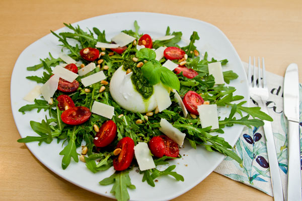 Bild zeigt einen Teller mit Burrata, Rucola, Tomate und Pesto alla Genovese.