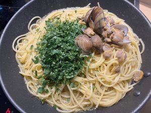 Spaghetti, Muscheln und Petersilie wird in der Pfanne vermengt.
