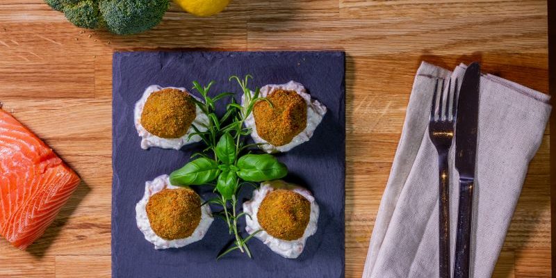 Bild zeigt Brokkoli Kugeln mit Mozzarella gefüllt, auf einem Räucherlachs Ricotta Dip