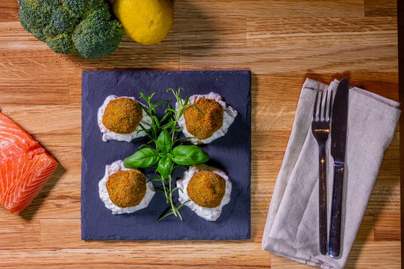Bild zeigt Brokkoli Kugeln mit Mozzarella gefüllt, auf einem Räucherlachs Ricotta Dip