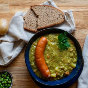 Das Bild zeigt einen Teller mit Erbseneintopf und Würstchen nach einem Rezept von Foodista-Hannover.
