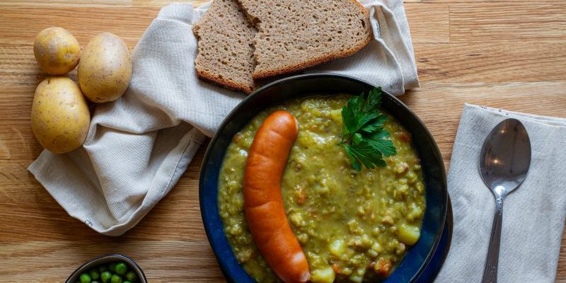 Das Bild zeigt einen Teller mit Erbseneintopf und Würstchen nach einem Rezept von Foodista-Hannover.
