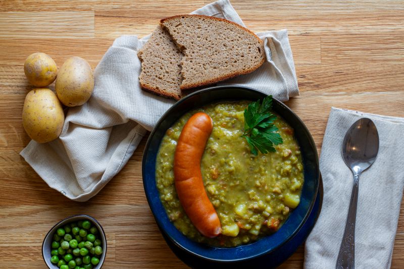 Das Bild zeigt einen Teller mit Erbseneintopf und Würstchen nach einem Rezept von Foodista-Hannover.